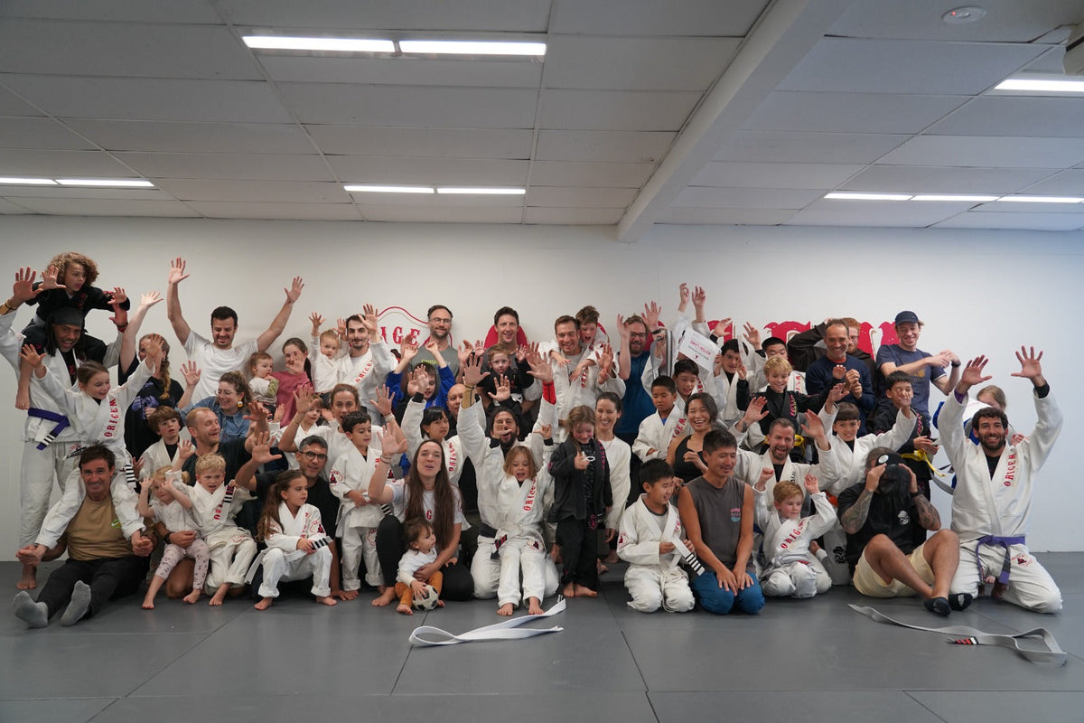Brazilian Jiu-Jitsu students and instructors posing together at Origem BJJ academy
